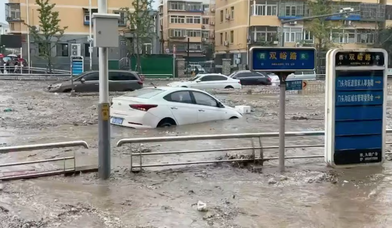 Cars are partially submerged as water gushes on a flooded street, after Typhoon Doksuri made landfall and brought heavy rainfall, at the Mentougou district, in Beijing, China July 31, 2023, in this still image obtained from social media video. Video obtained by Reuters/via REUTERS